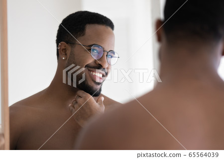 Smiling african American man in glasses look in bathroom mirror 65564039