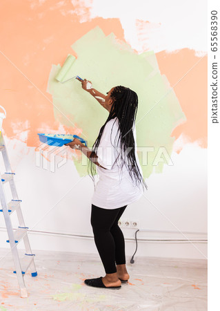 Repair in the apartment. Happy young woman paints the wall with paint. 65568390