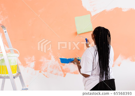 Repair in the apartment. Happy young woman paints the wall with paint. Repair in the apartment. Happy young woman paints the wall with paint. 65568393