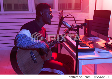 African american professional musician recording guitar in digital studio at home, music production technology concept. 65568525
