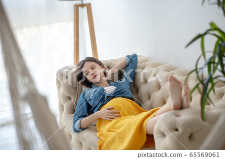 Young pregnant woman in a jeans jacket looking thoughtful 65569061