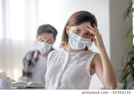 Young woman in a facial mask having a headache Young woman in a facial mask having a headache 65569116