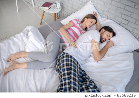 Pregnant young woman and her husband having a nap together 65569239
