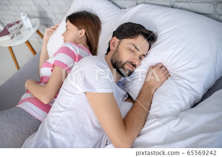 Pregnant young woman in a striped tshirt and her husband sleeping 65569242
