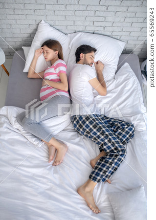 Pregnant young woman in a striped tshirt and her husband napping 65569243