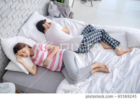 Pregnant young woman in a striped tshirt and her husband resting 65569245