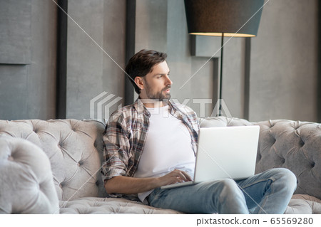 Pensive man in a plaid shirt with a laptop. 65569280