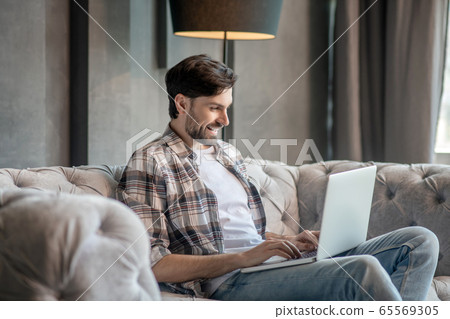 Young adult man with laptop on the couch. Young adult man with laptop on the couch. 65569305
