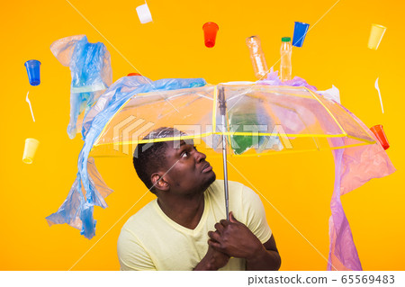 World Environment Day, plastic recycling problem and environmental disaster concept - Surprised african american man looking on trash on yellow background. World Environment Day, plastic recycling problem and environmental disaster concept - Surprised african american man looking on trash on yellow background. 65569483
