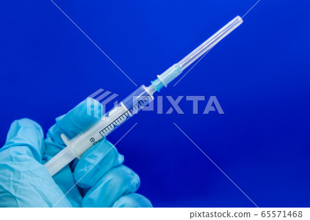 White 2 ml syringe macro in hand in blue glove White 2 ml syringe macro in hand in blue glove 65571468