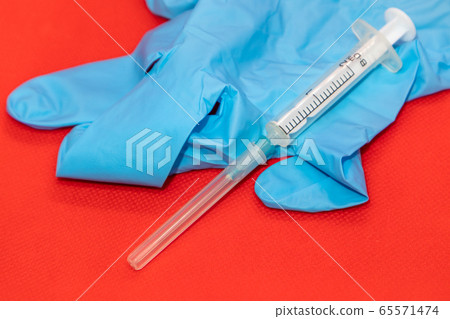 White 2 ml syringe macro on red, blue rubber glove White 2 ml syringe macro on red, blue rubber glove 65571474