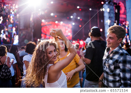 Rear view of group of young friends dancing at summer festival. 65571534