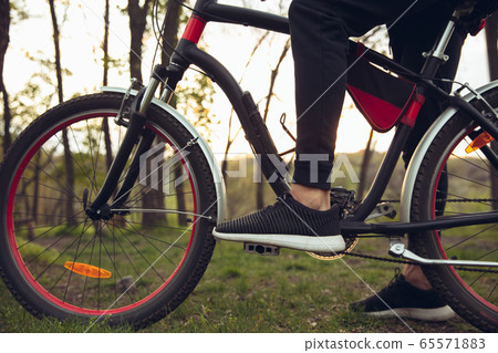 Close up of young man having fun near countryside park, riding bike, traveling at spring day Close up of young man having fun near countryside park, riding bike, traveling at spring day 65571883