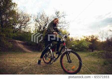 Young man having fun near countryside park, riding bike, traveling at spring day Young man having fun near countryside park, riding bike, traveling at spring day 65571933