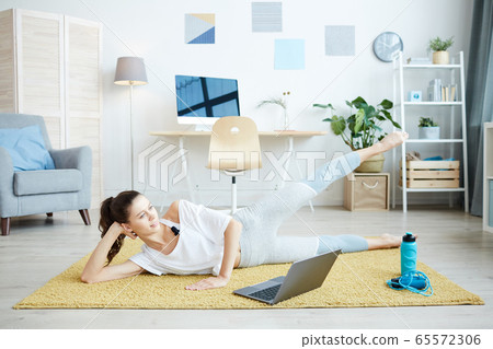 Smiling Young Woman Working Out at Home Smiling Young Woman Working Out at Home 65572306