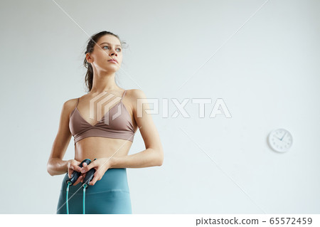 Portrait of Sportive Young Woman Holding Jumping Rope 65572459