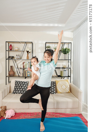 Woman exercising with baby in hands Woman exercising with baby in hands 65573178