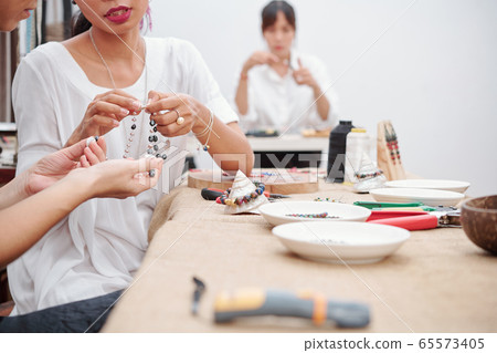 Women making beauticul necklace 65573405