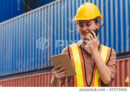 The logistics female staff is standing in front of colorful containers at habour warehouse The logistics female staff is standing in front of colorful containers at habour warehouse 65573608