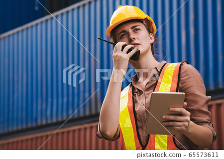 The logistics female staff is standing in front of colorful containers at habour warehouse The logistics female staff is standing in front of colorful containers at habour warehouse 65573611