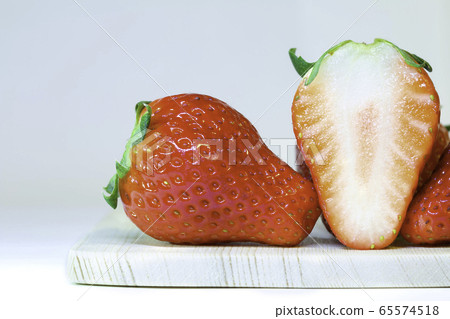 Close up of Red strawberries full and half placing on a wooden plate 65574518