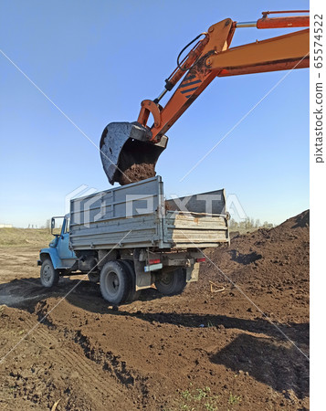 excavator machine loading soil into truck body. 65574522