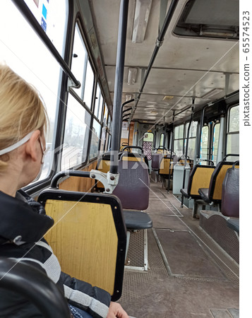 woman in mask riding in empty trolley bus during woman in mask riding in empty trolley bus during 65574523