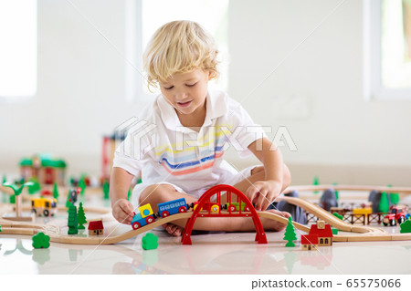 Kids play wooden railway. Child with toy train. Kids play wooden railway. Child with toy train. 65575066