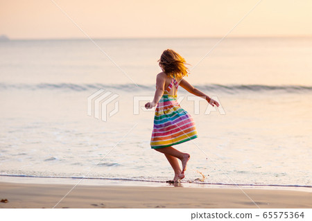 Child playing on ocean beach. Kid at sunset sea. Child playing on ocean beach. Kid at sunset sea. 65575364