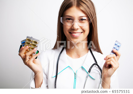 Doctor holds in his hands the prescribed pills for patient 65575531