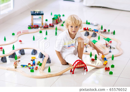Kids play wooden railway. Child with toy train. 65576032