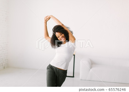 An African American young woman doing physical exercises standing in a mat An African American young woman doing physical exercises standing in a mat 65576246