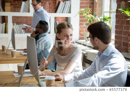 Friendly male and female colleagues having conversation talking in office 65577379