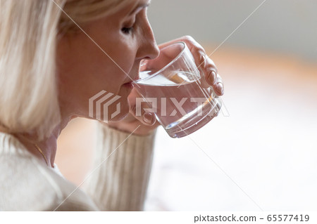 Dehydrated healthy senior woman feeling thirsty drinking water, 65577419