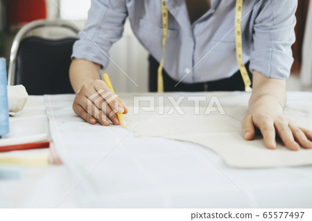 Closeup young tailor working with sewing pattern Closeup young tailor working with sewing pattern 65577497