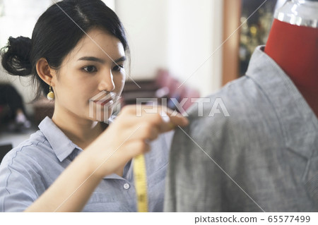 The tailor taking measurements of jacket on 65577499