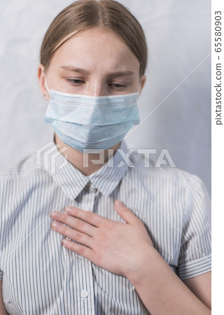 Close-up, teenage girl, feeling sick cough and sore throat and pain, wearing a protective medical mask, stay home, disease prevention and disease protection pandemic covid 19. 65580903