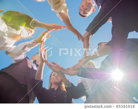 A group of friends make a circle shape out of their hands. The concept of world peace. 65581018
