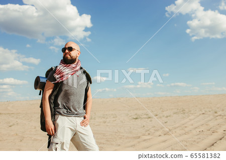 Tourist with backpack traveling through desert 65581382