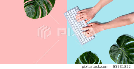 Person using a computer keyboard with tropical leaves Person using a computer keyboard with tropical leaves 65581832