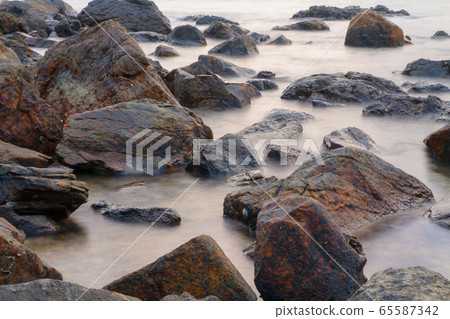 The smooth wave on sea near rock before The smooth wave on sea near rock before 65587342