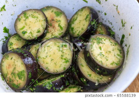 in a bowl, raw, struck eggplant in a marinade with herbs, dill in a rustic natural form. Preparation 65588139