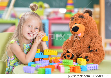 Little girl playing with teddy bear and colorful plastic blocks Little girl playing with teddy bear and colorful plastic blocks 65589186