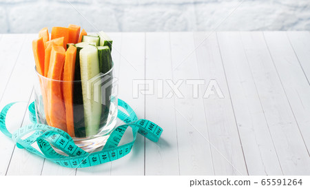 Fresh carrot and cucumber sticks in a glass. Centimeter measurement of volume. Concept of dietary nutrition. Copy space. Fresh carrot and cucumber sticks in a glass. Centimeter measurement of volume. Concept of dietary nutrition. Copy space. 65591264
