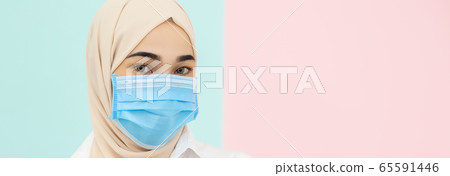 Muslim woman wearing medical mask for prevent infection virus on pastel color background.  65591446