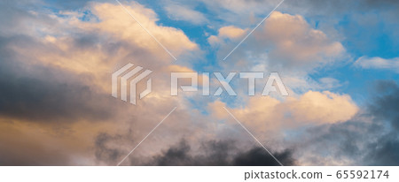 Beautiful colorful panorama of summer golden fluffy clouds illuminated by disappearing rays at sunset Beautiful colorful panorama of summer golden fluffy clouds illuminated by disappearing rays at sunset 65592174