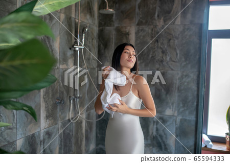 Brunette female standing in shower in night dress, wiping with towel Brunette female standing in shower in night dress, wiping with towel 65594333