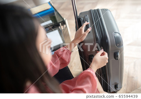 Close-up of female hands zipping her suitcase 65594439