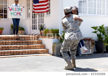 African American woman and her daughter standing welcoming an African American soldier African American woman and her daughter standing welcoming an African American soldier 65595006