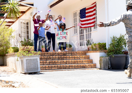 African American male soldier wearing uniform and his family standing by their house African American male soldier wearing uniform and his family standing by their house 65595007